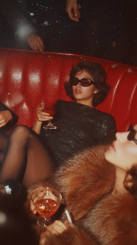 Woman wearing sunglasses relaxing on a red booth during a night out