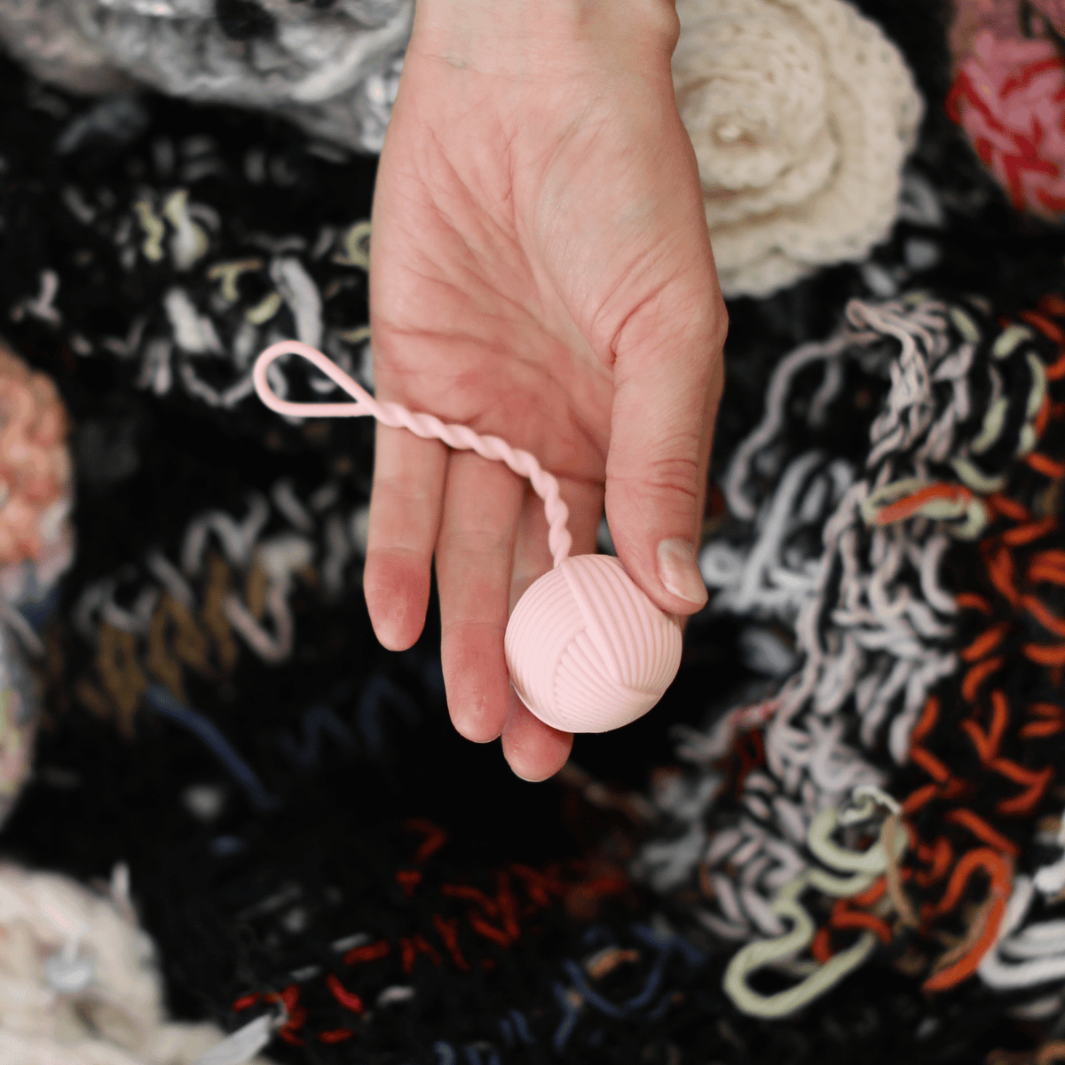 Hand holding the pink yarn-shaped vibrator